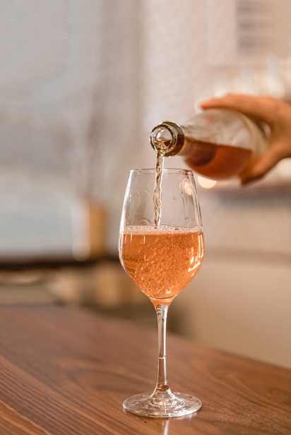 A blush-colored cider is poured into a wine-like glass